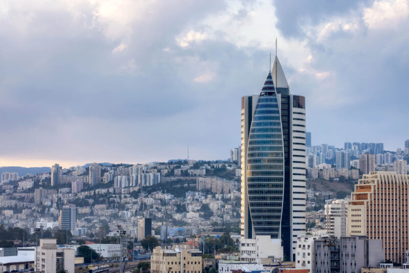 תמונת נושא של המאמר על דירה להשקעה כנכס לטווח ארוך המציג את בניין הטיל בחיפה על רקע העיר והכרמל עם שמיים מעוננים